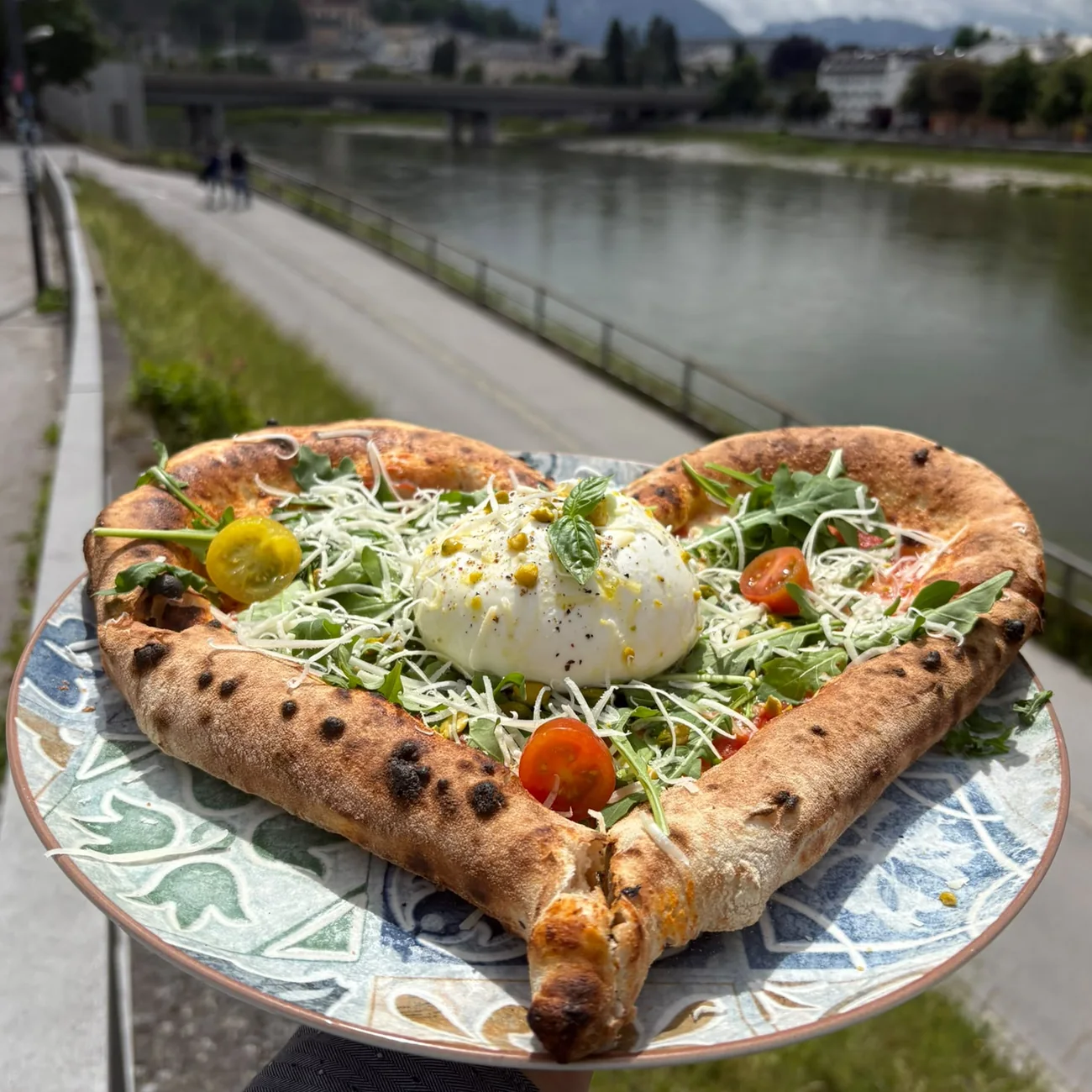Herzförmige Pizza mit Burrata vor der Salzach in Salzburg